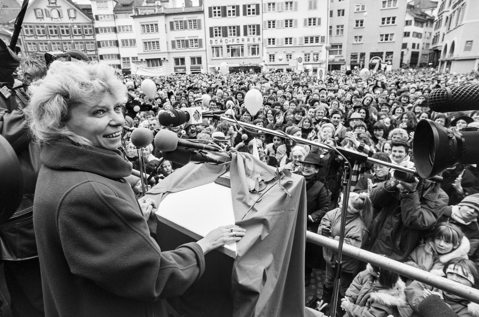 Photo black and white of Christiane Brunner, in front of a microphone, facing a huge crowd