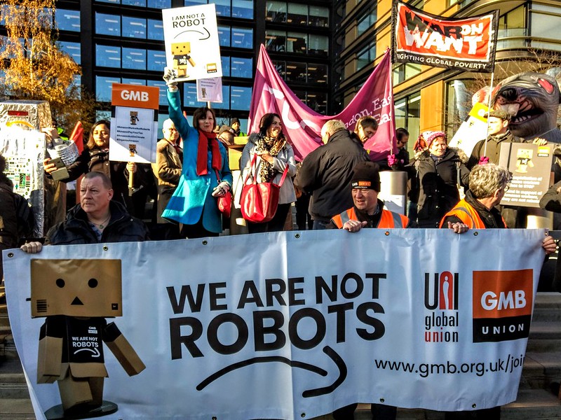 Image depicting a protest with the caption "We are not Robots"